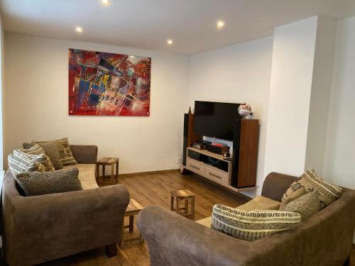 a living room with two couches and a flat screen tv at Dovolenkový dom eLAra in Smižany