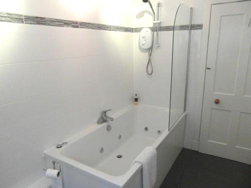 y baño blanco con bañera y ducha. en Amazing cottage with private indoor swim pool and hot tub en Grantown on Spey