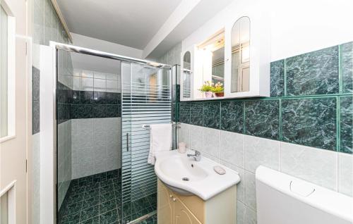 baño de azulejos verdes con lavabo y ducha en Awesome Apartment In Marina With Lake View en Marina