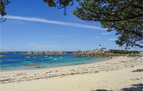 einen Strand mit Menschen im Wasser und einem Leuchtturm in der Unterkunft Nice Home In Plouguerneau With Wifi in Plouguerneau