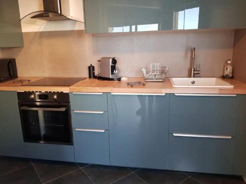 a kitchen with blue cabinets and a sink at Splendide T2 face à la mer, terrasse, wifi in Hendaye
