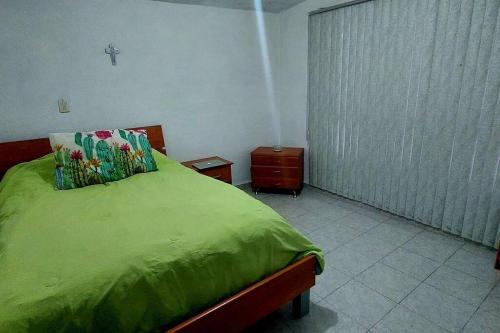 a bedroom with a bed with a green blanket at Casa Rosa in Tepotzotlán