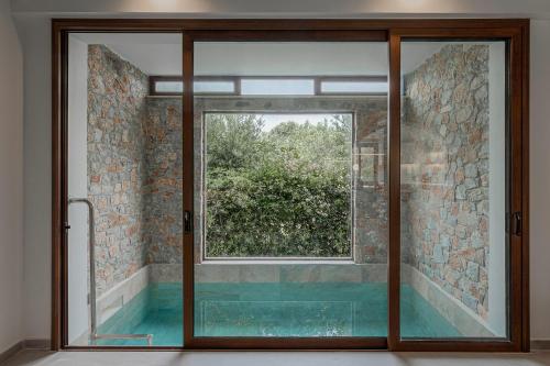 a glass door in a bathroom with a window at Villa Nineta in Tavronitis