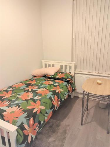 a bedroom with a bed with a flowered blanket and a table at havilahomes in Manchester