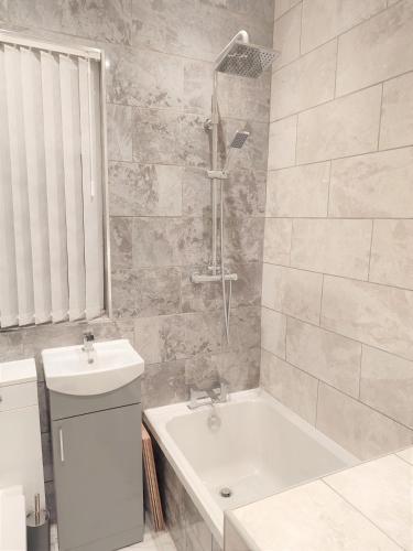 a bathroom with a tub and a sink and a shower at havilahomes in Manchester