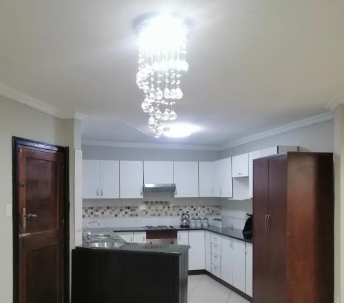 a kitchen with white cabinets and a chandelier at Villa Pretoria in Pretoria