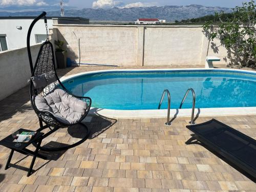 a black chair sitting next to a swimming pool at Apartman Matej with pool Povljana in Povljana