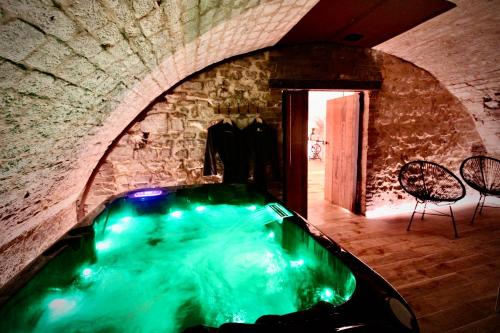 uma banheira de hidromassagem numa sala de pedra com cadeiras e uma mesa em Spa Gaalor***** - Jacuzzi & Sauna à Rouen em Rouen