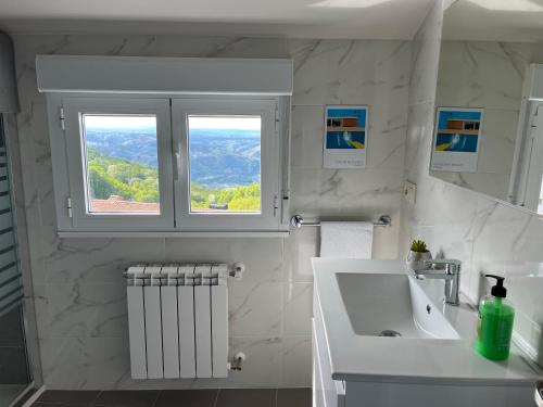ein weißes Badezimmer mit einem Waschbecken und zwei Fenstern in der Unterkunft Casa Manuela in Castro Caldelas