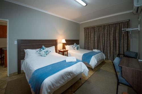 ein Hotelzimmer mit 2 Betten und einem Schreibtisch in der Unterkunft @ Marula in Mokopane