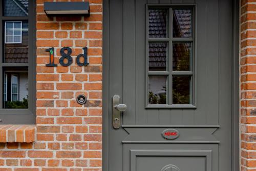 une porte grise d'une maison en briques avec un numéro dessus dans l'établissement Haus Möhre, à Tinnum