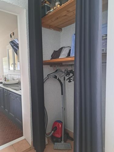 a room with a kitchen with a desk with a vacuum at Studio avec jardin à 5 min du Parc Walibi in Roquefort