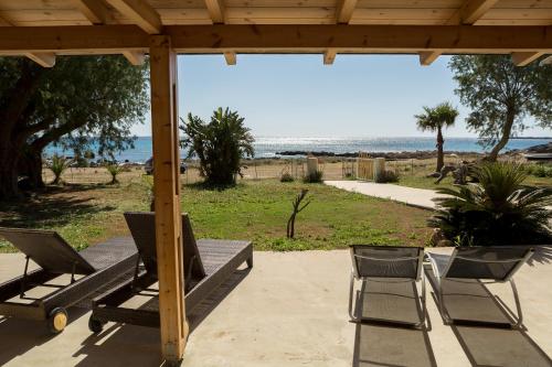 een patio met stoelen en een tafel en uitzicht op het strand bij Mera Beachfront House - Falasarna in Falasarna