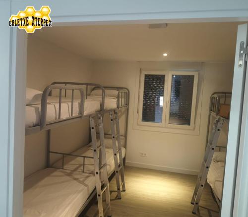 a room with three bunk beds and a window at Erletxe Aterpea in Lezo