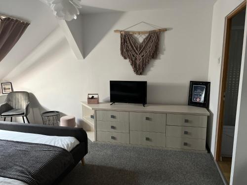 a bedroom with a bed and a dresser with a television on it at Bulevard mansards in Satu Mare