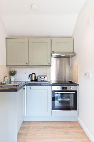 a kitchen with white cabinets and a stove top oven at The Pigsty in Buxton