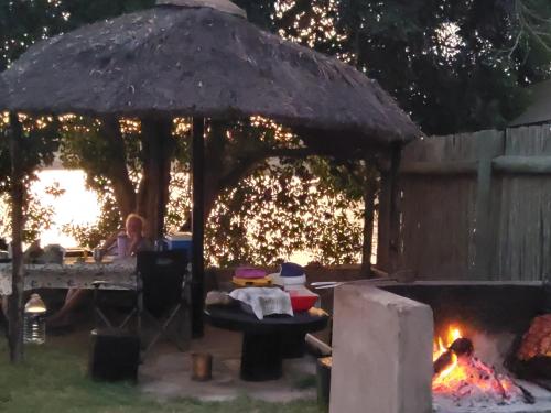 a woman sitting at a table under a gazebo with a fire at Von Bach Dam Resort in Okahandja