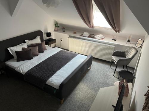 a bedroom with a bed and a chair and a window at Bulevard mansards in Satu Mare