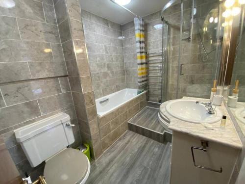 a bathroom with a toilet and a sink and a tub at Sentinel 2 Bed Apartment in NW London in London
