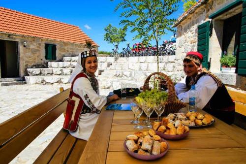 Duas pessoas sentadas numa mesa com comida. em Kuća za odmor Varoš em Vrlika