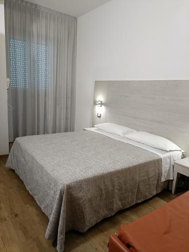 a bedroom with a large bed and a window at Hotel Ricci in Rimini