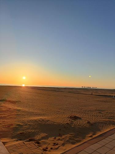 a sunset on a beach with the sun setting at Hotel Ricci in Rimini