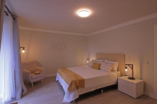 a bedroom with a large bed and a chair at Solar Arco de São Jorge in Santana