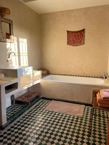 ein Badezimmer mit einer Badewanne und einem karierten Boden in der Unterkunft Dar Tasmayoun in Aït Ourir