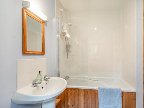 een witte badkamer met een wastafel en een bad bij Cruinn in Taynish