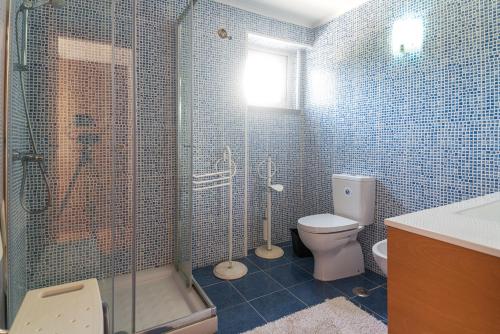 e bagno piastrellato blu con servizi igienici e doccia. di Villa Cassandra a Sintra