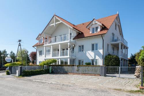 a white house with a fence in front of it at PIONOW Rodzinne Apartamenty Urocza 10 in Krynica Morska