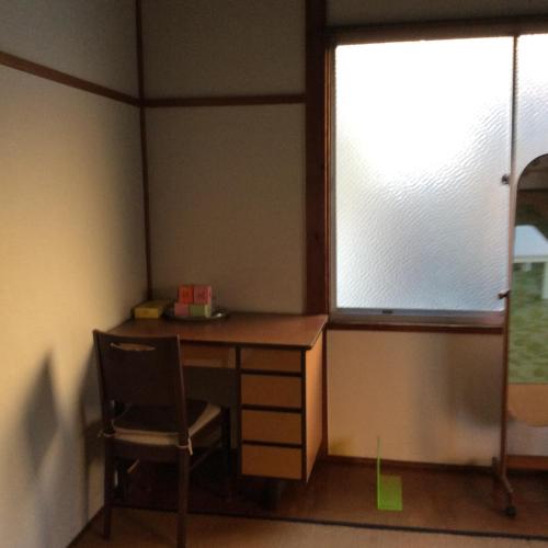 a desk and a chair in a room with a window at ハーモニーイン in Osaka