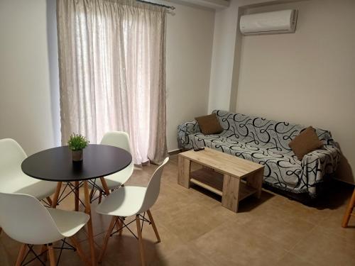 uma sala de estar com um sofá, uma mesa e cadeiras em ALMIRIKI Studios & Apartments em Alykes