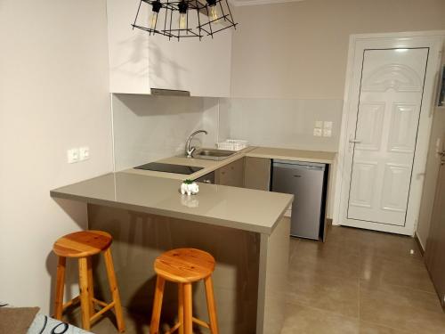 uma cozinha com um balcão e dois bancos em ALMIRIKI Studios & Apartments em Alykes