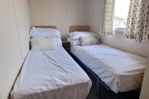 two twin beds in a small room with a window at Lovely Caravan Nearby The Beach In Hunstanton, Norfolk Ref 23071c in Hunstanton