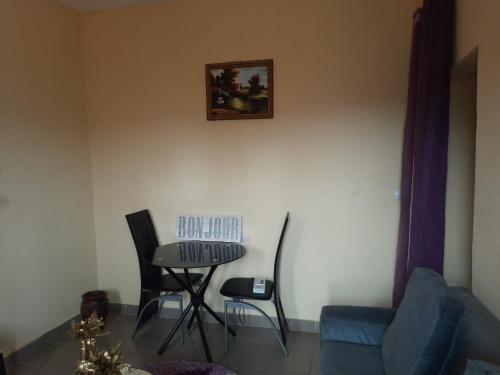 un soggiorno con tavolo e 2 sedie di LNIMMO - DEPOU - Studio meublé Ahmadou Ekie climatisé et avec internet illimité avec forage a Yaoundé