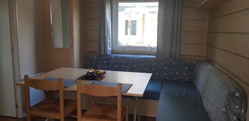 a table and chairs with a blue couch in a room at Splendide mobil-home in Narbonne