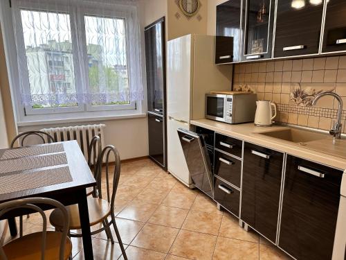 a kitchen with a table and a kitchen with a microwave at Apartament Dąbrowskiego - Gliwice in Gliwice