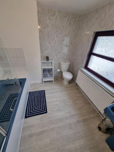 baño con bañera, aseo y ventana en Brookmount House, en Omagh