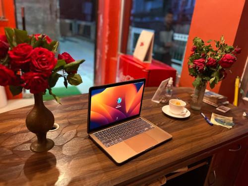 un ordenador portátil sentado en una mesa de madera con flores en Hotel Crescent, en Srinagar