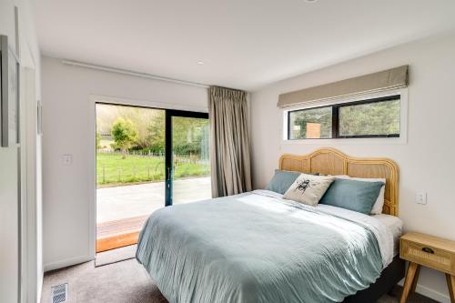 a bedroom with a bed and a large window at River Range Cottage - Havelock North Holiday Home in Havelock North