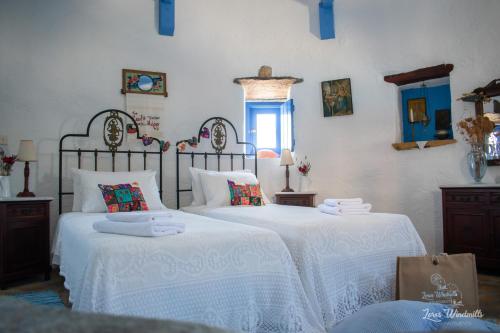 een slaapkamer met 2 bedden met witte lakens en een raam bij Leros Windmills in Panteli