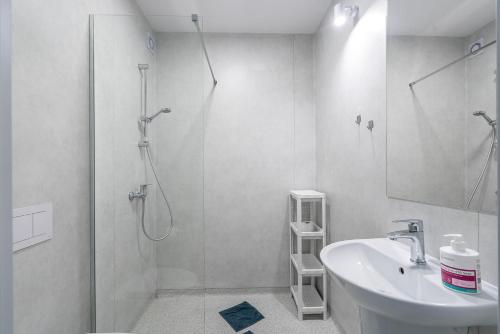 biała łazienka z prysznicem i umywalką w obiekcie PIONOW Pokoje Hotelowe - adults only w mieście Krynica Morska