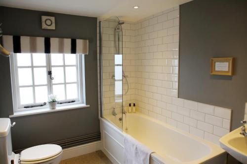 y baño con bañera, aseo y lavamanos. en The Barn @Bourne Eau House, en Bourne