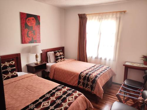 a hotel room with two beds and a window at Apartamento 32 Juana de Arco in Quito