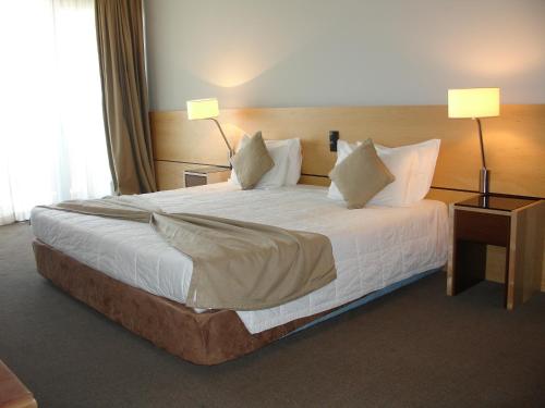 a large bed in a hotel room with two lamps at VIP Executive Azores Hotel in Ponta Delgada