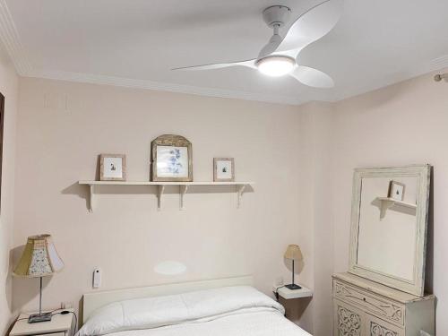 een witte slaapkamer met een bed en een plafondventilator bij APTO. DE 1 DORMITORIO EN PRIMERA LINEA DE PLAYA. ISLA CANELA in Huelva