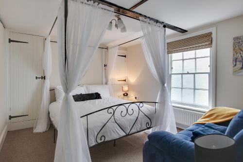 a bedroom with a canopy bed with white curtains at The Red House Maldon in Maldon