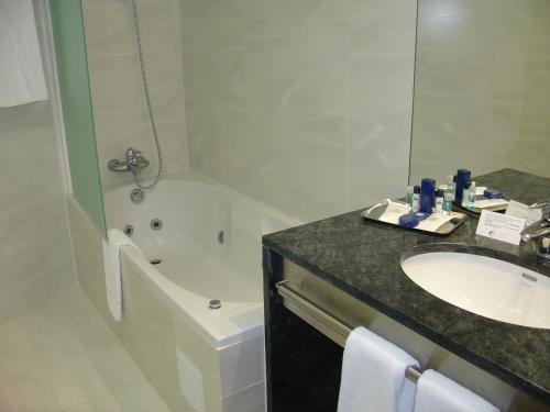 a bathroom with a sink and a toilet and a tub at VIP Executive Azores Hotel in Ponta Delgada