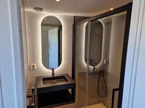 uma casa de banho com um lavatório e um espelho em Nice holiday home with sauna and jacuzzi near the Wadden Sea em Tzummarum